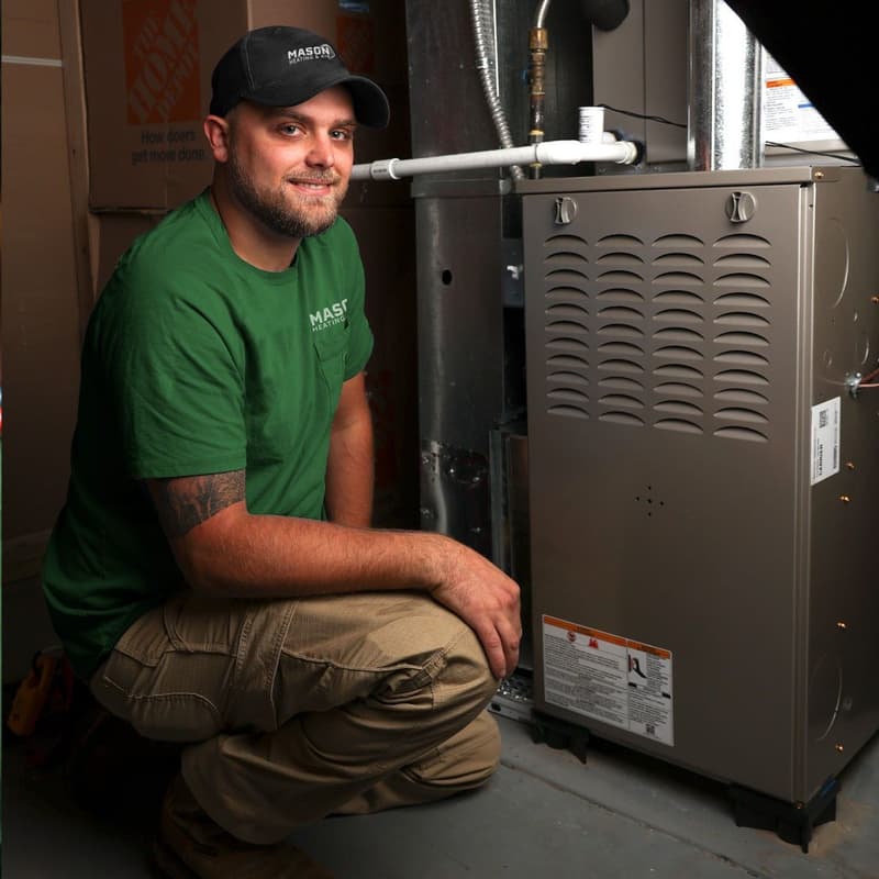 Technician crouching next to gas furnace